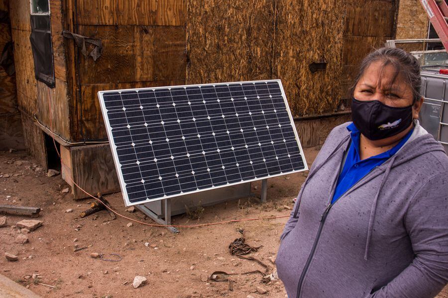 Sandra Howe, a Sacred Wind Communications representative, poses in front of the solar panel installed at Devona Juan’s home east of Thoreau.
