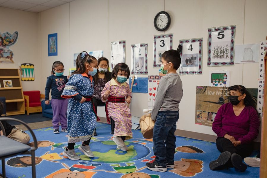 Students, left to right, Teagan Toledo and Leianna Lucero dance as Koah Baca drums in the Hemish classroom for the language immersion program at the Walatowa Head Start in Jemez Pueblo.
